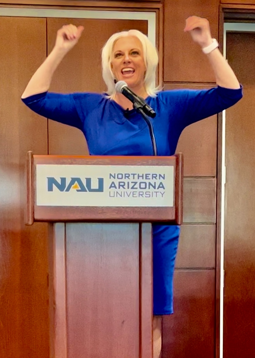 Jessica at Northern Arizona University podium with arms raised