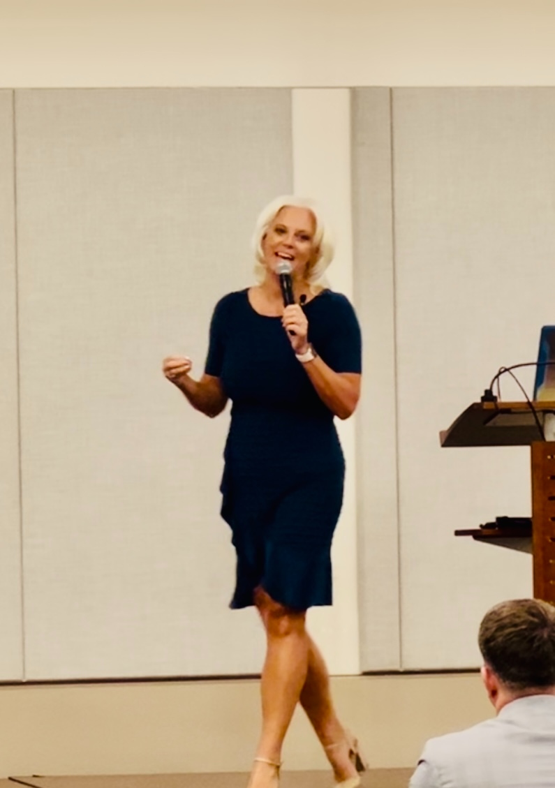 Jessica on stage in navy dress at conference
