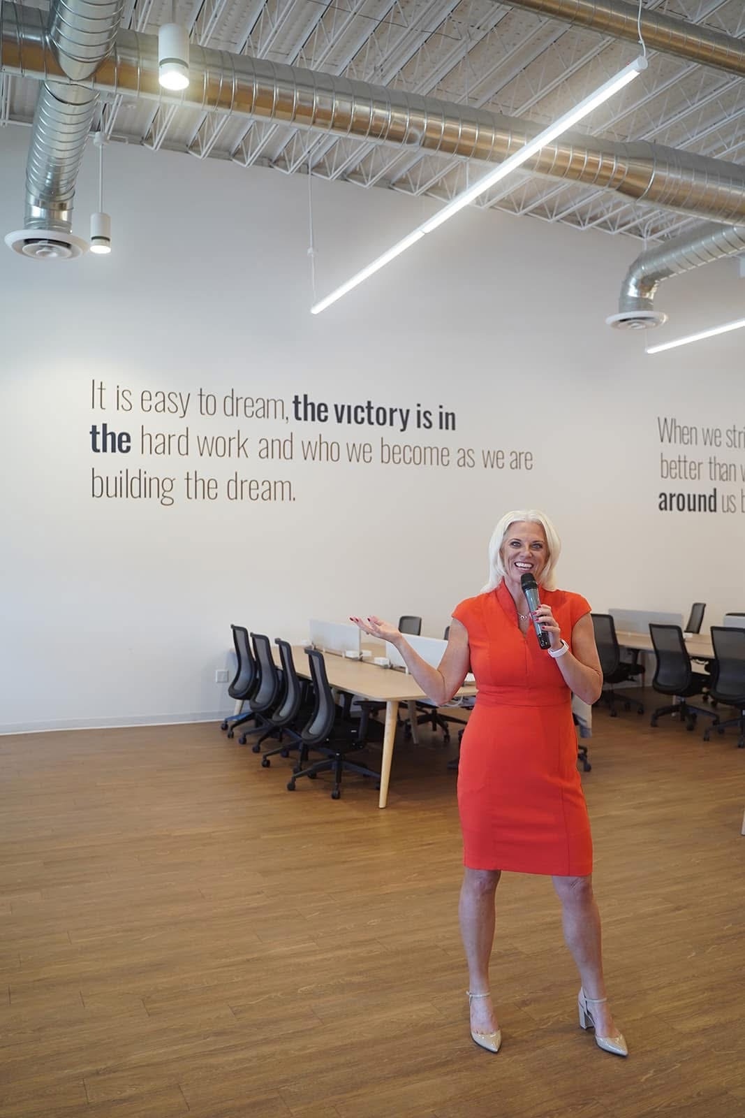 Jessica speaking in modern office with motivational wall quotes